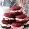 Red Velvet Cookie Sandwiches on white plate stacked with pink, red, white sprinkles