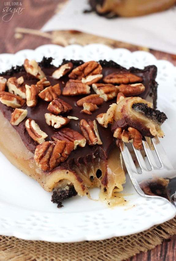 A fork digging into a slice of no-bake caramel chocolate pecan pie