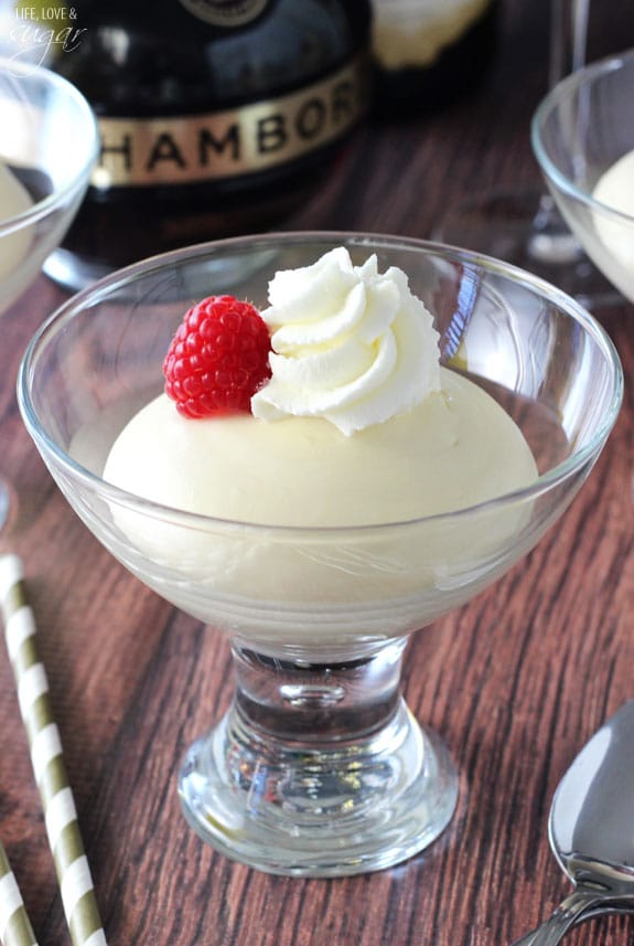 Close up of Mousse in a glass bowl with whipped cream and a raspberry on top