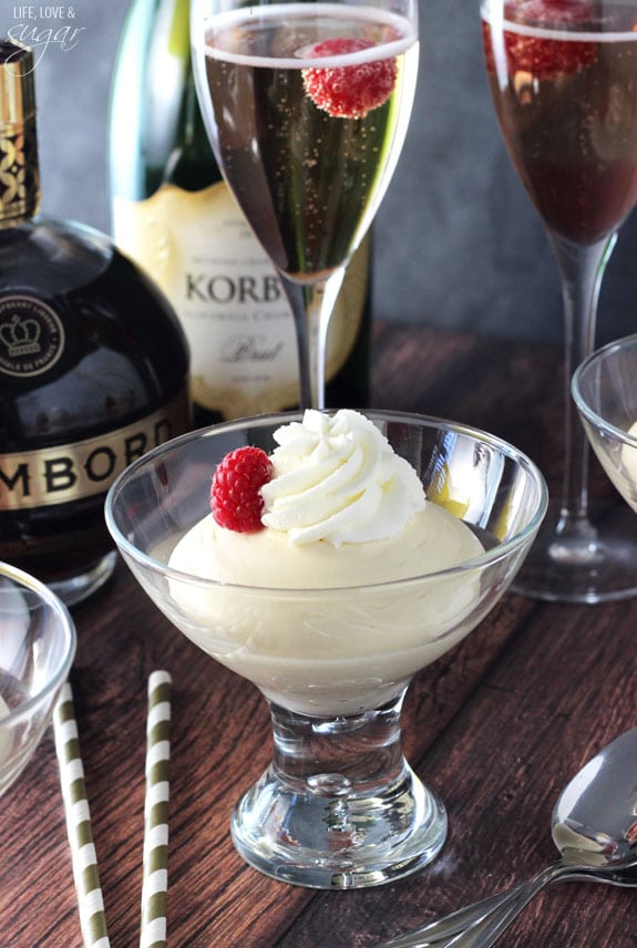 White mousse in a glass with whipped cream and a raspberry on top