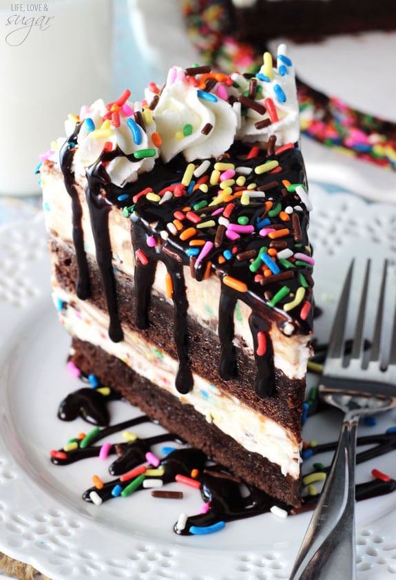 A big piece of ice cream cake on a plate with a glass of milk behind it