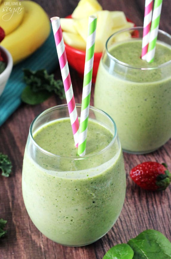 Two green smoothies with two colorful straws in a short glass cups