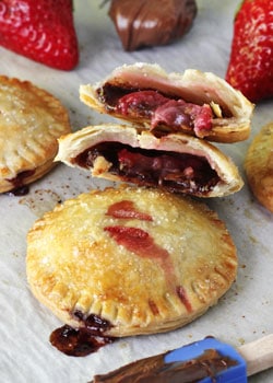 Strawberry Nutella Hand Pies on wax paper, one pie halved