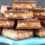 Pecan Caramel Turtle Candy Bars stacked on blue stand