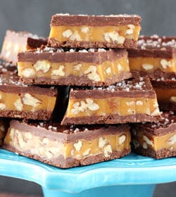 Pecan Caramel Turtle Candy Bars stacked on blue stand