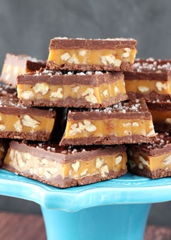 Pecan Caramel Turtle Candy Bars stacked on blue stand