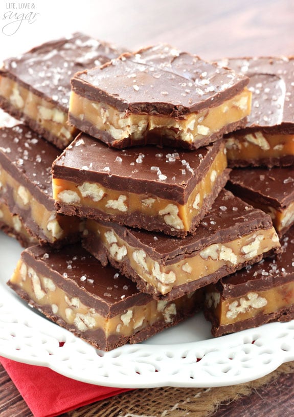 Pecan Caramel Turtle Bars stacked on a white plate with a bite out of one