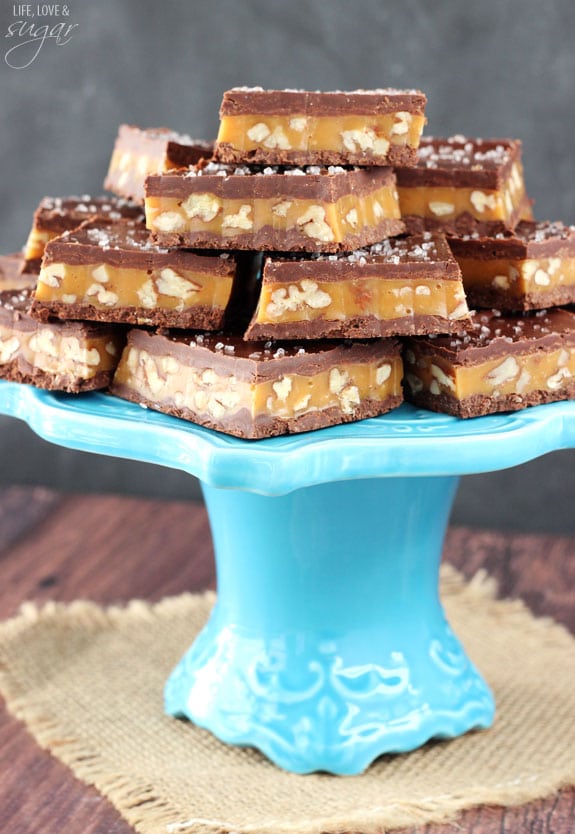 Pecan Caramel Turtle Bars stacked on a blue cake stand