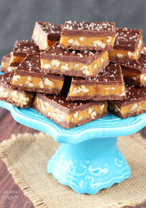 Pecan Caramel Turtle Bars stacked on a blue cake stand