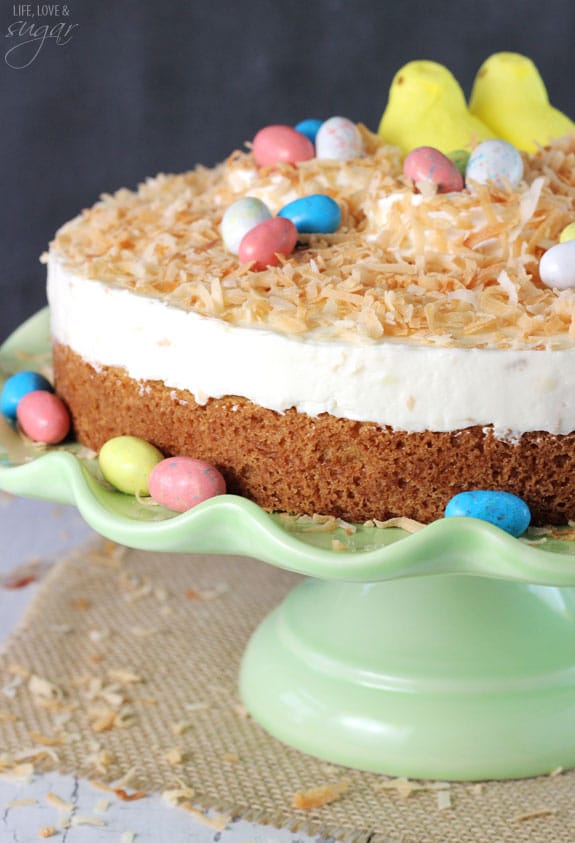Coconut Blondie Cheesecake on a green cake stand garnished with marshmallow Peeps and easter egg candies