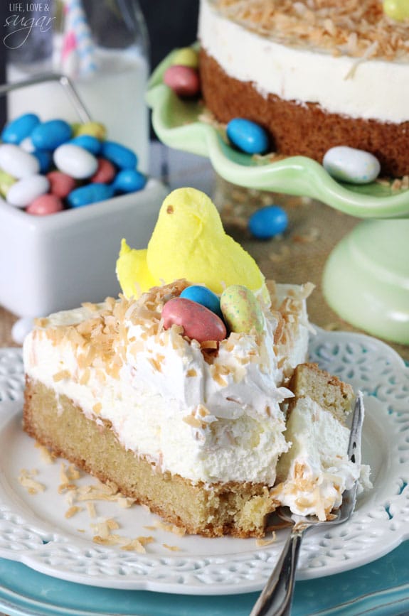 A slice of Coconut Blondie Cheesecake on a plate with a bite on a fork