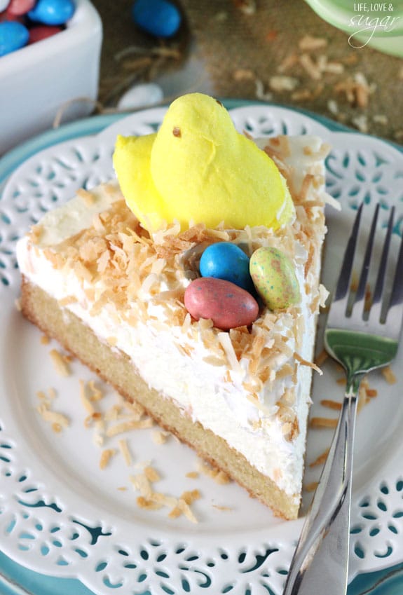 Coconut Blondie Cheesecake slice topped with a marshmallow Peep and easter egg candies on a plate