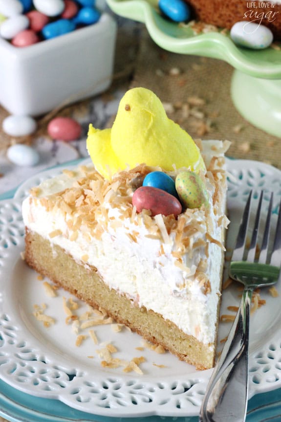 A slice of Coconut Blondie Cheesecake on a plate topped with a marshmallow Peep and egg candies