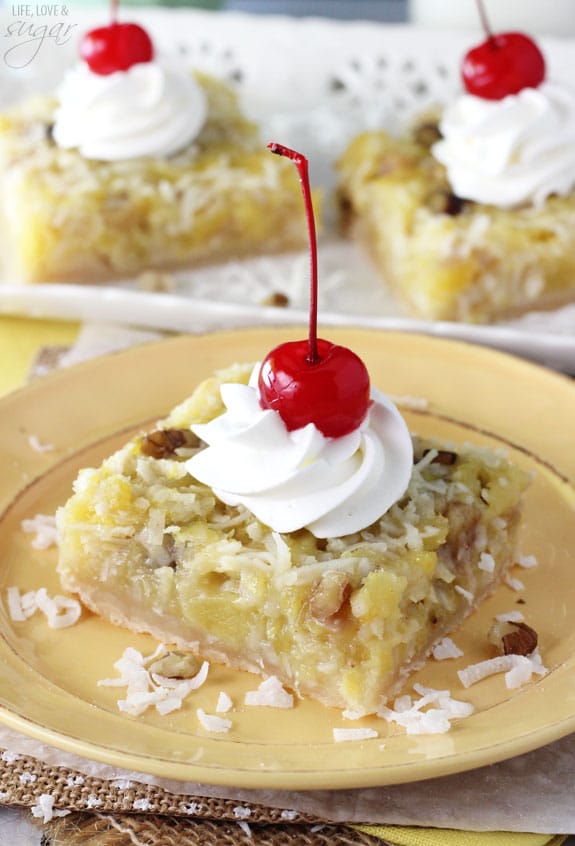 Pineapple Coconut Bar on a yellow plate with whipped cream and a cherry on top