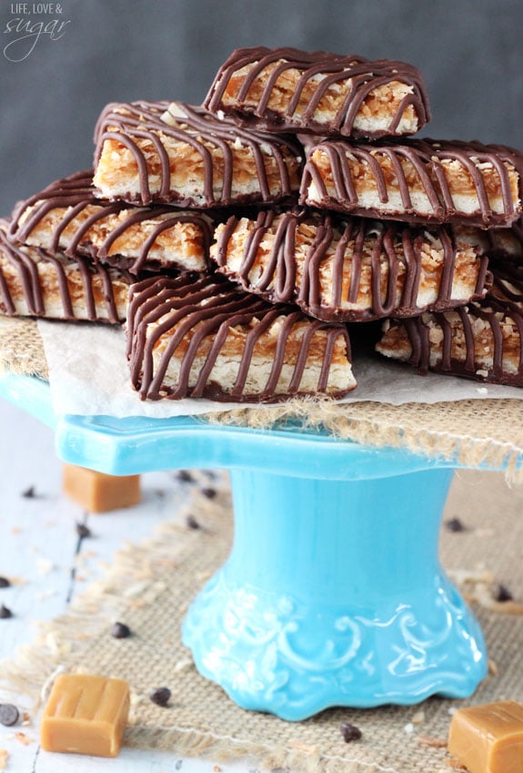 A blue cake stand holding a batch of samoa cookie bars