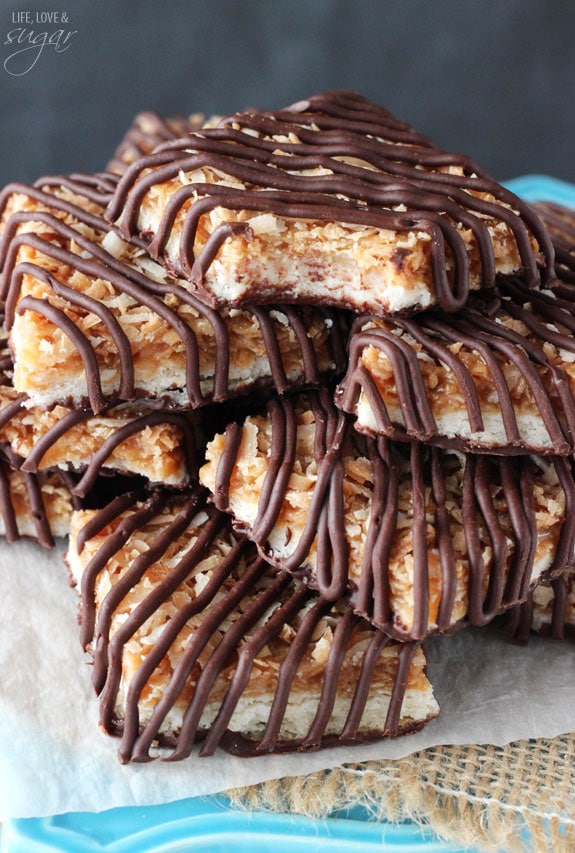 A pile of chocolate caramel coconut bars with the top one missing a bite