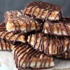 Caramel coconut chocolate shortbread cookie bars piled onto a tall cake stand