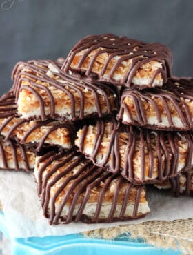 Caramel coconut chocolate shortbread cookie bars piled onto a tall cake stand