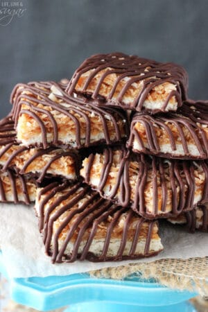Caramel coconut chocolate shortbread cookie bars piled onto a tall cake stand