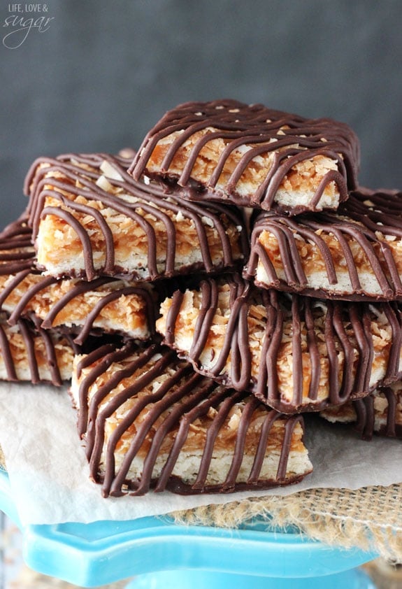 Caramel coconut chocolate shortbread cookie bars piled onto a tall cake stand