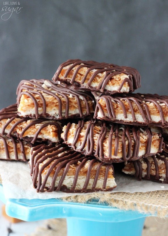 A stack of samoa cookie bars on top of a teal cake stand