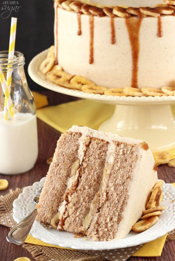 Bananas Foster Layer Cake slice on a plate in front of a whole cake on a cake stand