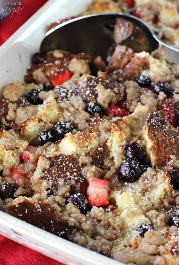 Strawberry and Blueberry French Toast Casserole in a baking dish with a spoon