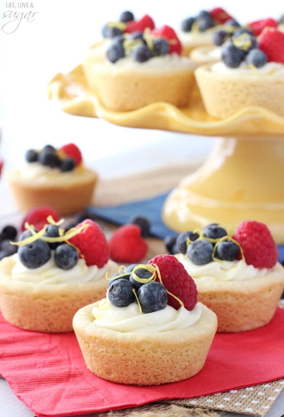 Berry Lemon Cheesecake Cookie Cups on a red napkin and on a yellow cake stand