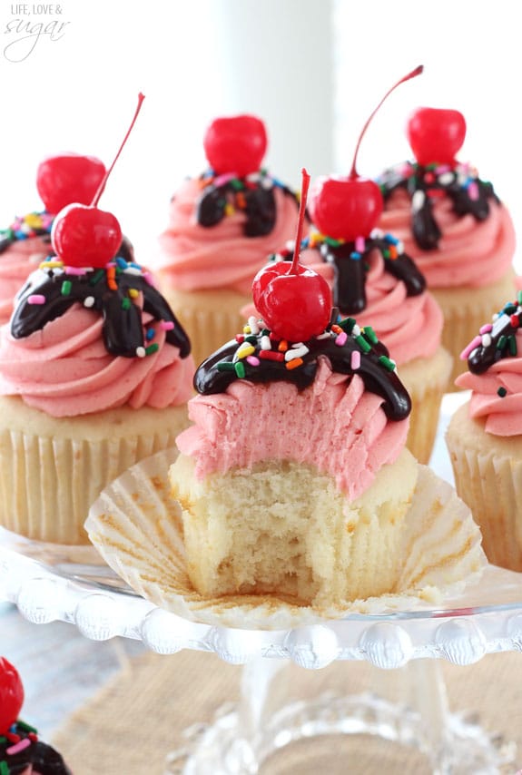Strawberry Sundae Cupcakes on a cake stand with a bite out of one