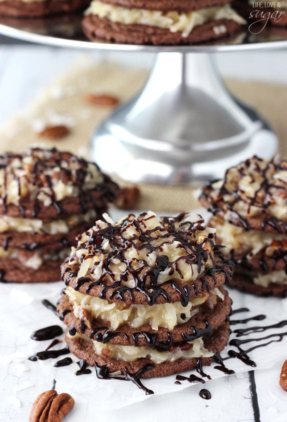 Three German Chocolate Cookie Stacks that has been drizzled with chocolate sauce and surrounded by pecans