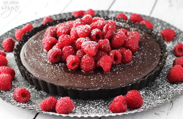 Side view of a Oreo crust Nutella tart topped with fresh raspberries and powdered sugar