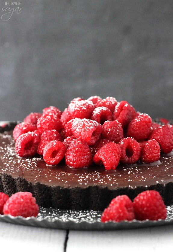 Close up side view of a Nutella tart topped with fresh raspberries and powdered sugar