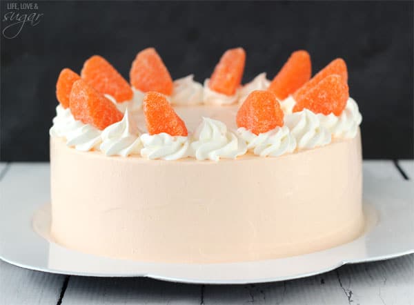 Side view of a whole Orange Creamsicle Ice Cream Cake topped with swirls of whipped cream and candied oranges