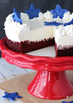 Red Velvet Blondie Cheesecake on red stand with slice missing