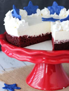 Red Velvet Blondie Cheesecake on red stand with slice missing