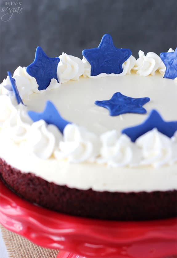 Close-up view of Red Velvet Blondie Cheesecake on a red cake stand topped with blue stars