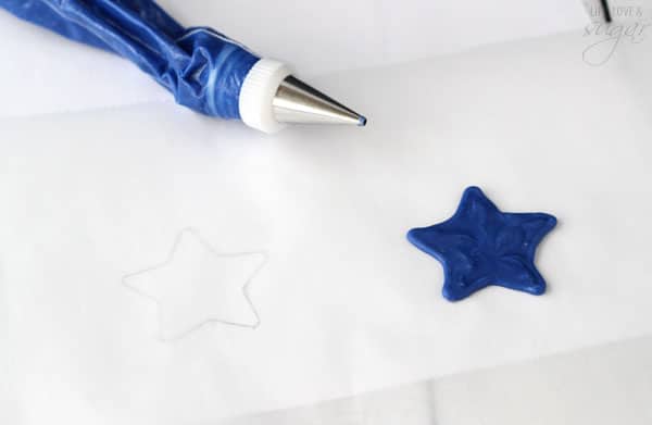 Blue frosting in a piping bag and a blue frosting star on parchment