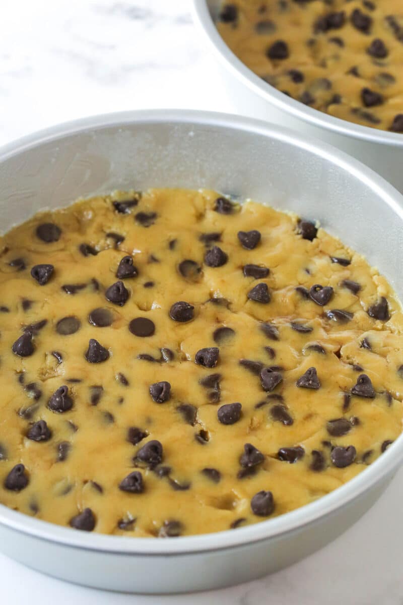 Pressing chocolate chip cookie dough into a round pan