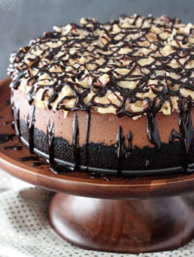 A whole German Chocolate Cheesecake on a wooden stand