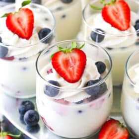 close up of glass cup of panna cotta with berries in it