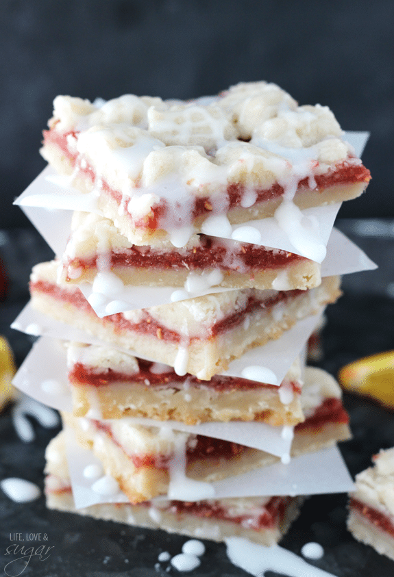 Raspberry Orange Shortbread Bars stacked between squares of parchment paper