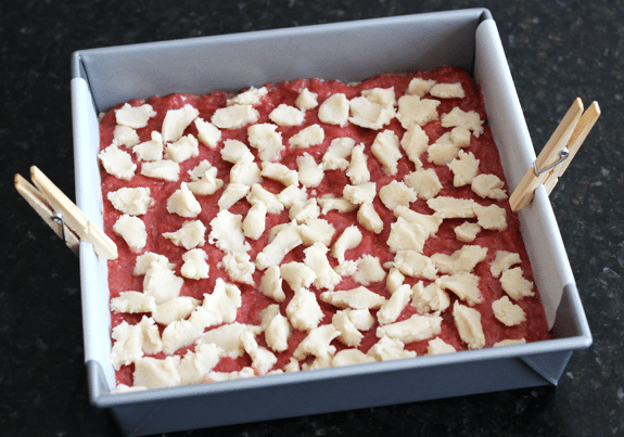 Unbaked Raspberry Orange Shortbread Bars in a parchment-lined baking pan