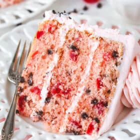 A slice of cherry chocolate chip cake on a white plate