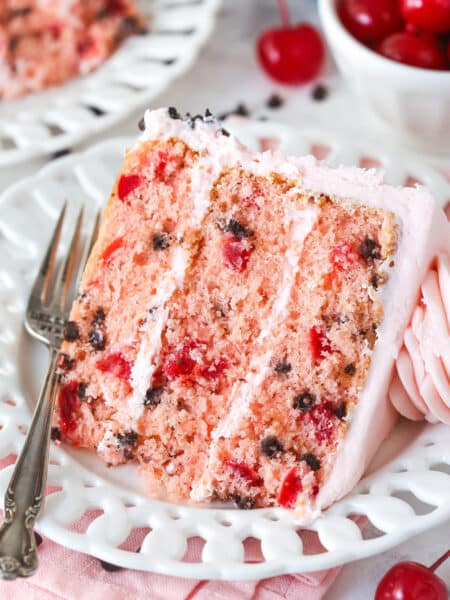 A slice of cherry chocolate chip cake on a white plate