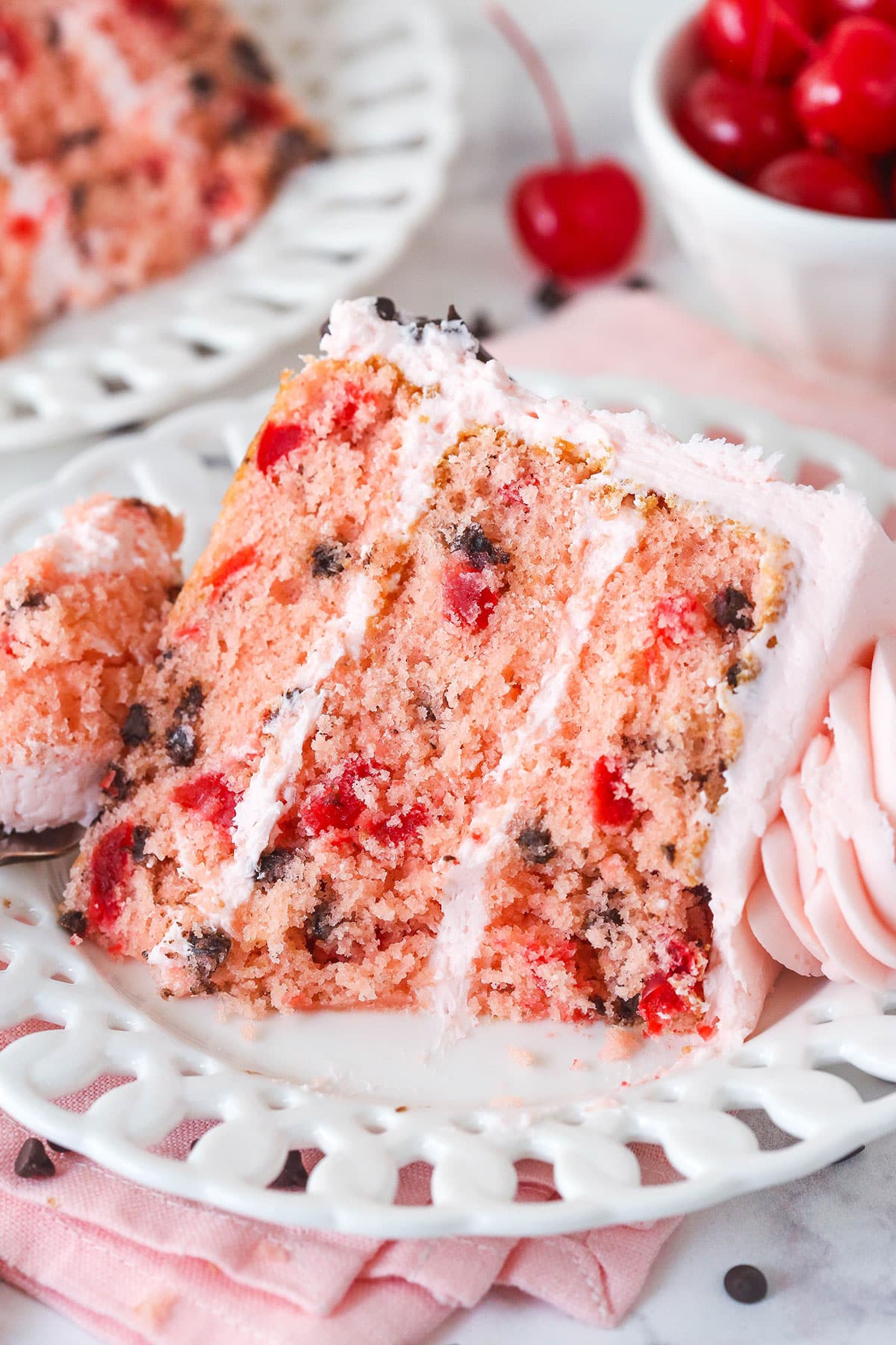 This cherry chocolate chip cake is moist, tender, and full of cherry and chocolate flavor in every single bite. A slice of cherry chocolate chip cake on a white plate