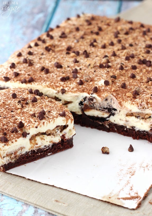 Chilled tiramisu topped with chocolate chips. A square has been cut from the main dish and set aside.