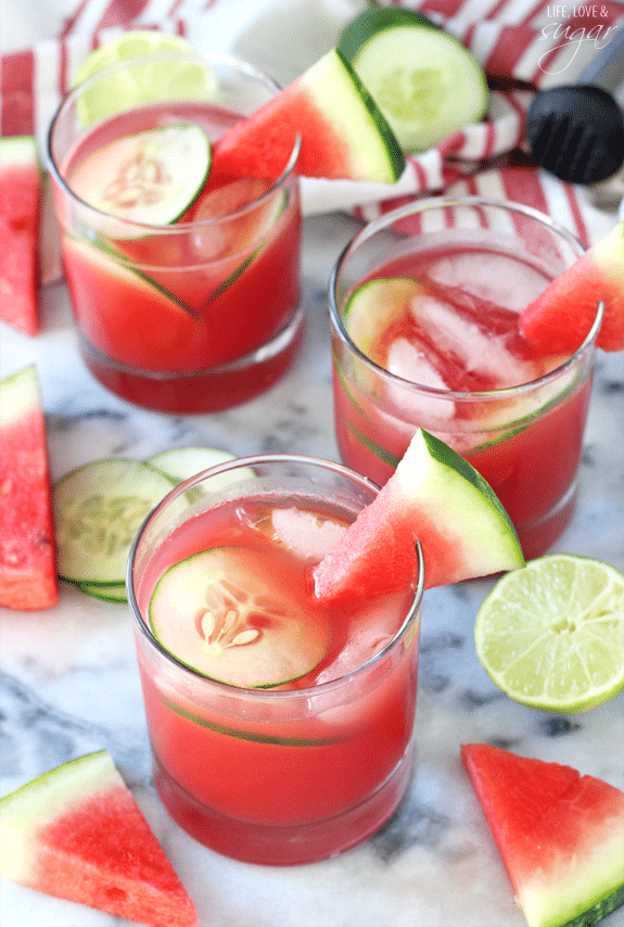 Overhead view of a few glasses of Watermelon Elderflower Cocktail garnished with watermelon wedges and cucumber slices