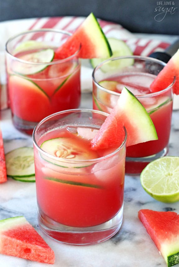 Watermelon Elderflower Cocktail in short glasses garnished with watermelon wedges and cucumber slices