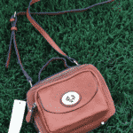 A Brown Purse with an Adjustable Shoulder Strap on the Grass