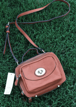 A Brown Purse with an Adjustable Shoulder Strap on the Grass